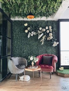 the living room is decorated with greenery and flowers on the wall, along with two chairs