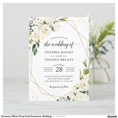 a wedding card with white flowers and greenery