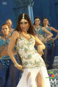 a woman in a white dress is dancing with other dancers behind her on the stage