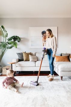 a woman and her baby playing with a vacuum