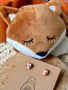 a brown stuffed animal sitting on top of a wooden table next to a card with the word hello kitty