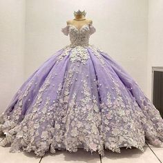 a purple and white ball gown with flowers on the skirt is displayed in front of a mannequin