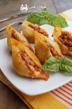 three stuffed shells with meat and sauce on a white plate next to a yellow napkin