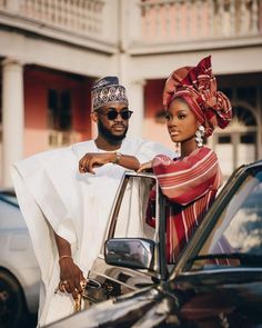 a man and woman standing next to a car