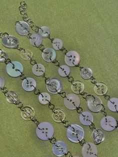 a bunch of buttons that are sitting on a green tablecloth with chains attached to them