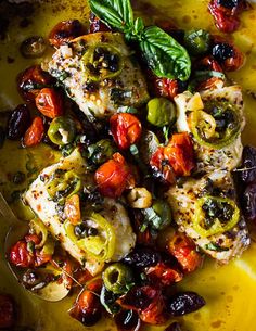 a yellow plate topped with chicken, tomatoes and olives