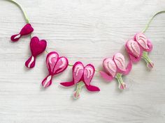 pink felt flowers and hearts are hanging from a string