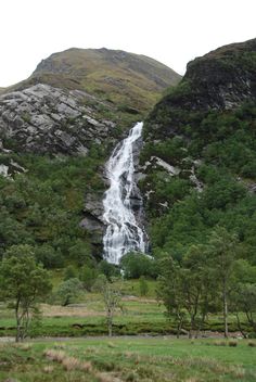 a large waterfall in the middle of a lush green field