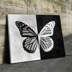 a black and white painting with a butterfly on it's back side next to a wall