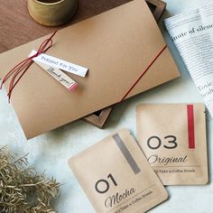 two brown envelopes sitting on top of a table next to a cup and paper