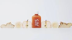 an orange juice bottle sitting on top of sliced apples with the word sut written in white