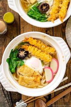 two white bowls filled with food on top of a wooden table