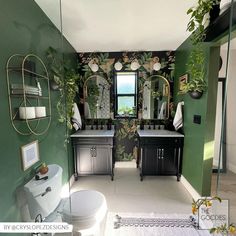 a bathroom with green walls and white flooring, decorated in black and gold accents