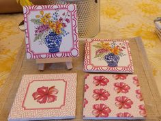 four coasters with flowers on them sitting on a table next to a tin can