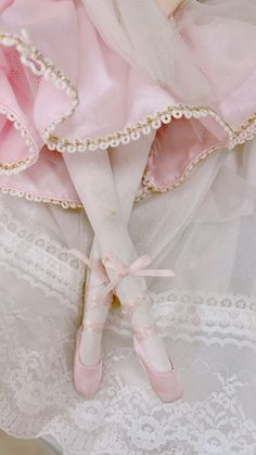 there is a doll with pink shoes on top of the dress and white laces