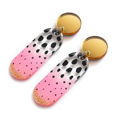 two pairs of pink and black polka dot earrings with gold accents on top of each pair