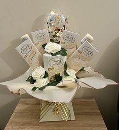 a vase filled with white flowers and confetti on top of a wooden table