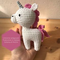 a crocheted unicorn is shown in front of a wooden background with text that reads unicono amigurmi traduzne in italiano schera di ms - eni