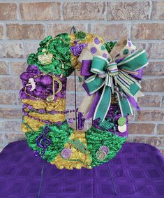 a purple and green wreath sitting on top of a table next to a brick wall