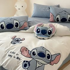 a bed with two pillows on top of it and a stuffed animal in the middle