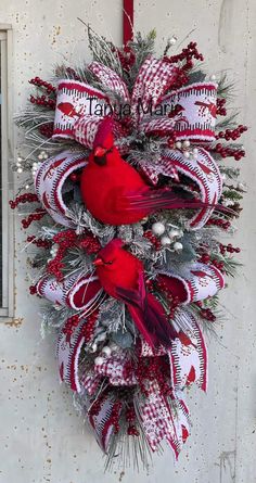 a christmas wreath hanging on the side of a building with two red birds sitting on it