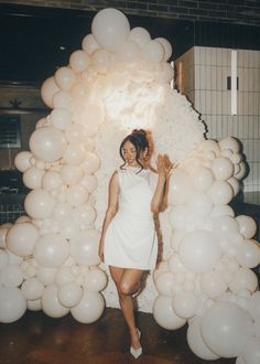 a woman standing in front of a bunch of balloons