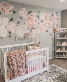 a baby's room decorated in pink and gray with roses on the wall, crib bedding, and rug