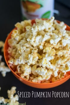 a bowl filled with popcorn sitting on top of a table next to a can of pumpkin