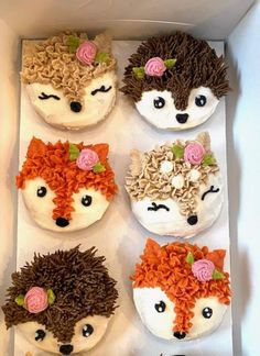 four cupcakes decorated like hedgehogs with flowers on them in a box