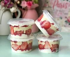 four plastic containers filled with strawberries on top of a table