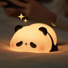 a lamp that looks like a panda bear laying on the ground with its eyes closed