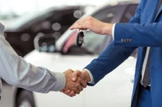 two men shaking hands over a car key