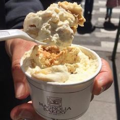 a person holding an ice cream sundae with a spoon in it's hand