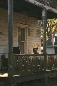 an old wooden porch with chairs on it