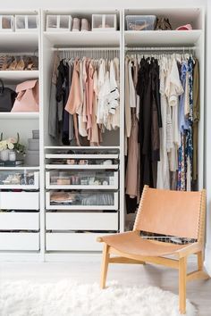 a white closet filled with lots of clothes and shoes next to a wooden chair on top of a rug