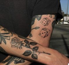 a man with tattoos on his arm and leg sitting in front of a street sign