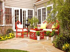 a patio with chairs, tables and potted plants on the side of the house