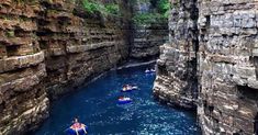 several people are rafting down a narrow river in the middle of a canyon with cliffs