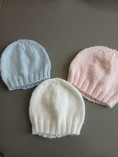 three knitted hats sitting next to each other on top of a gray countertop