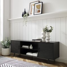 a black and white living room with vases on top of the entertainment center cabinet