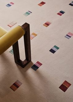 a yellow chair sitting on top of a white floor next to a wooden table with colorful squares