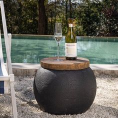 a bottle of wine sitting on top of a wooden barrel next to a glass of wine