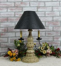 a table lamp sitting on top of a white counter next to flowers and greenery