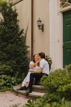 a man and woman sitting on the steps in front of a building with green doors