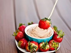 a plate topped with strawberries and a bowl of dip