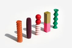 an assortment of colorful wooden toys on a white surface with shadows from the top to the bottom