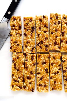 granola bars cut into squares on top of a cutting board with a knife next to them