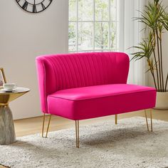 a pink chair sitting on top of a rug in front of a wall mounted clock