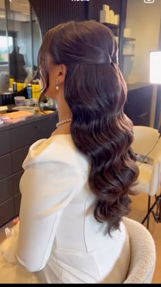 a woman sitting in a chair with her hair styled into a half - up ponytail