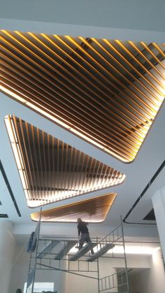 a man is climbing up the stairs in an office building with wooden slats on the ceiling